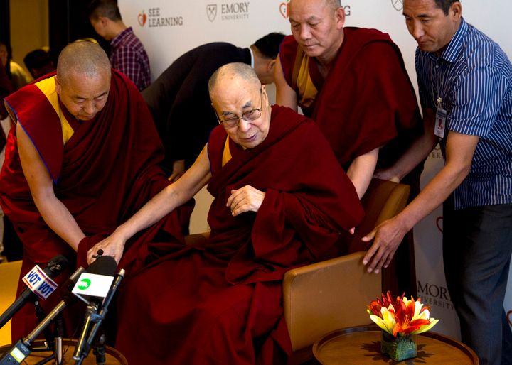 In this April 4, 2019, photo, Tibetan spiritual leader the Dalai Lama, center, is assisted by his aides as he arrives to interact with an audience of educators, in New Delhi, India. 