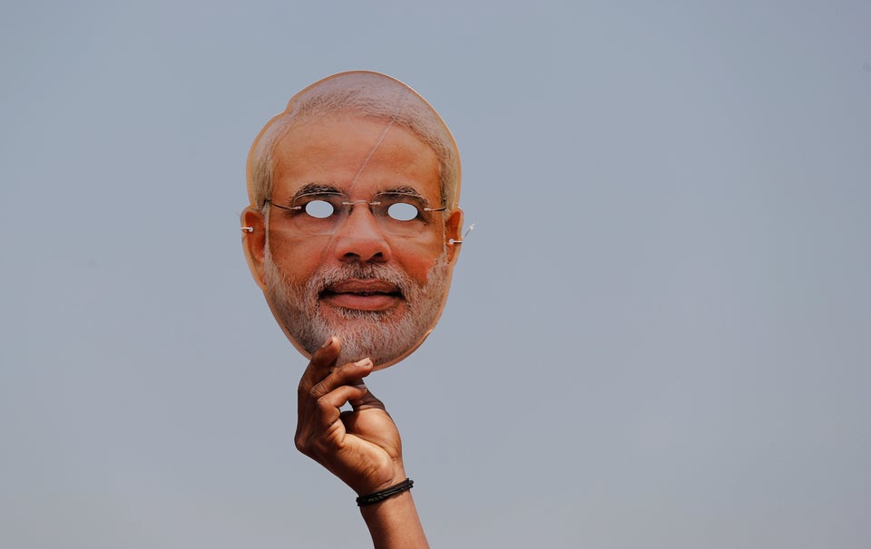 A BJP supporter holds a mask of Prime Minister Narendra Modi during an election rally in Meerut in Uttar...