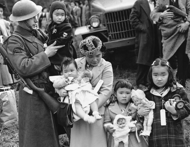 In this March 30, 1942 file photo, Cpl. George Bushy holds the child of Shigeko Kitamoto, center, as her family and other Japanese Americans are forcibly removed from Bainbridge Island, Washington, to be incarcerated during World War II.