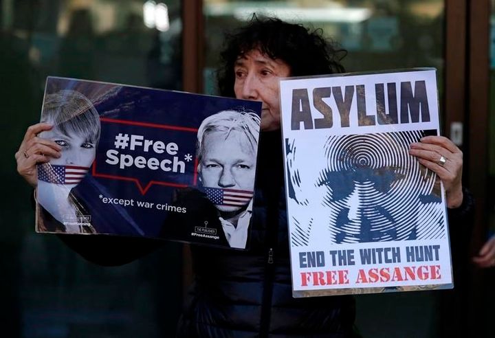 A protester holds banners reading "Free speech, except war crimes" and "Asylum: End the witch hunt, free Assange" outside Westminster Magistrates court in London on Thursday.