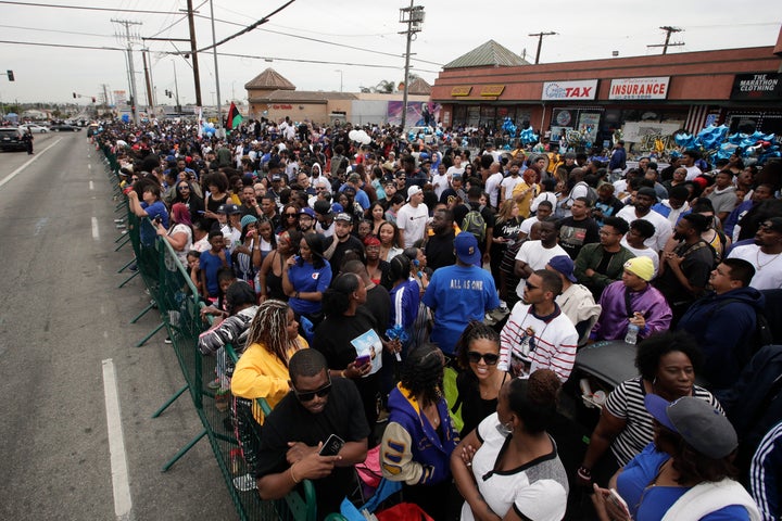 People gather outside The Marathon Clothing store to watch a funeral procession of rapper Nipsey Hussle, Thursday, April 11,