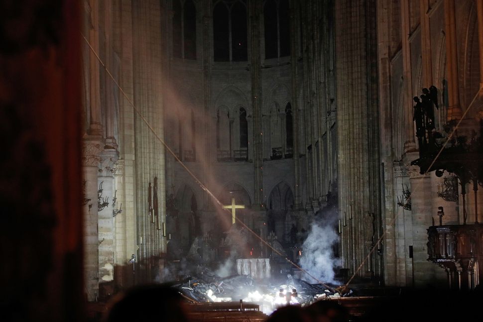 Smoke rises around the altar in front of the cross inside the Notre Dame cathedral.