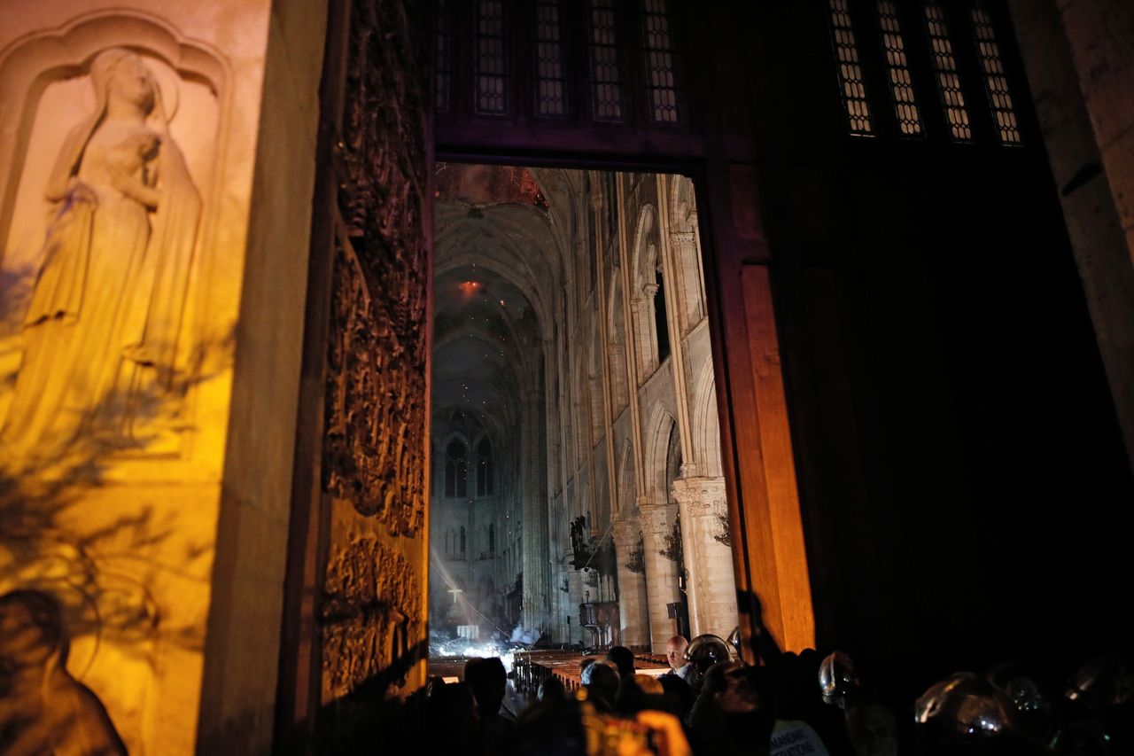 General view from the entrance shows smoke rising around the altar in front of the cross inside the Notre Dame cathedral.