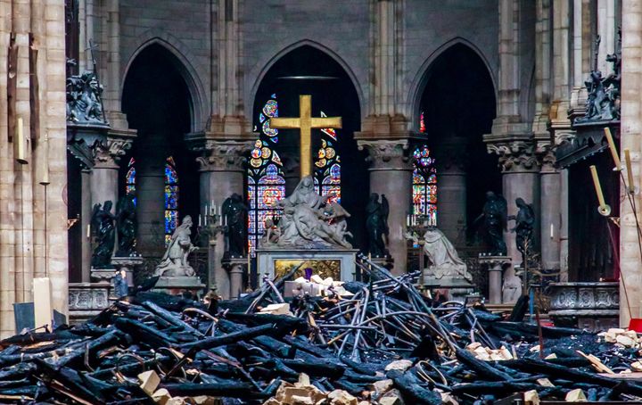 Blackened remains of Notre Dame's wooden roof framework lie on the cathedral floor.