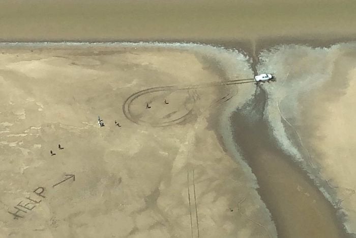 Shantelle Johnson and Colen Nulgit scratched HELP in the sand after their car became stuck in the mud