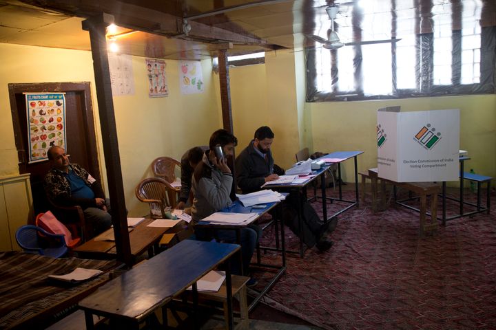 Election officers sit inside an empty polling station during the second phase of elections in Srinagar.