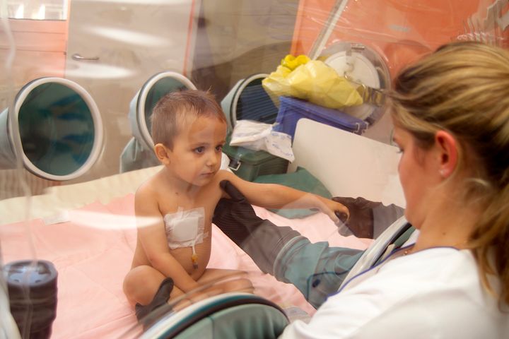 A child suffering from immune deficiencies sits in a sterile room at Necker Hospital For Children in Paris in 2002.
