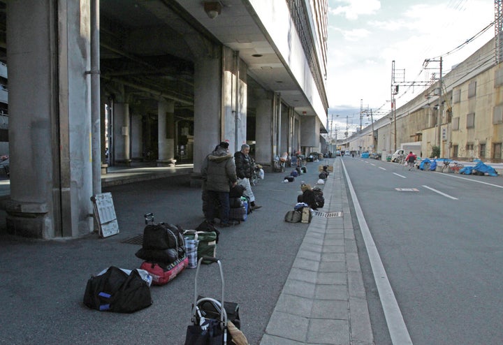 あいりん労働福祉センター前に荷物を置き、日雇い労働のあっせんを待つ人たち =2014年2月4日