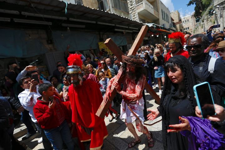 An actor carries a cross toward the Church of the Holy Sepulchre, traditionally believed to be the site of the crucifixion of Jesus Christ, during the Good Friday procession in Jerusalem's old city on April 19, 2019.
