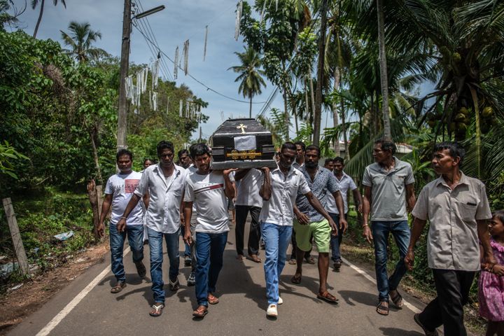 A coffin is carried to a burial site during a mass funeral at St Sebastian Church in Negombo, Sri Lanka