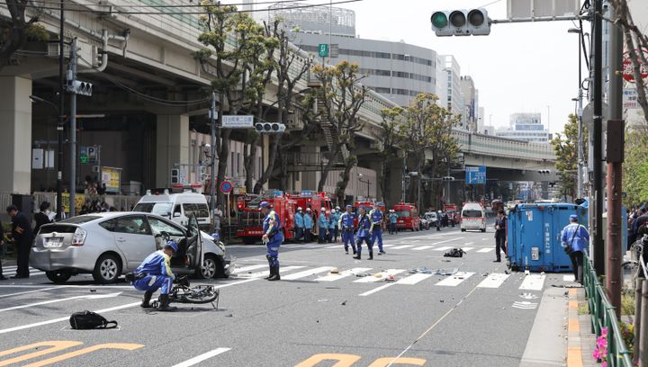 乗用車（左端）とごみ収集車（右端）が衝突し、歩行者がはねられた事故現場を調べる警察官＝4月19日、東京都豊島区