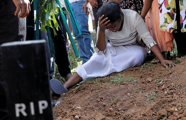 A woman holds her head in her hands during a mass funeral in Sri Lanka 