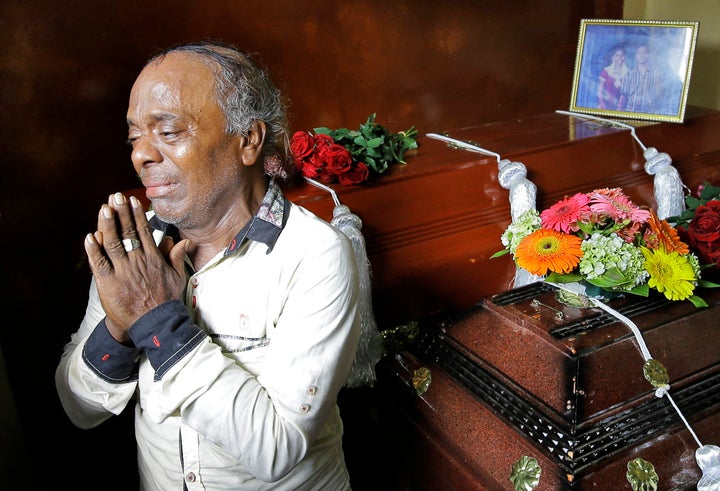 Baby Joseph Gomes prays next to the coffins of his family members who were killed in the Easter Sunday bombings in Colombo, Sri Lanka.