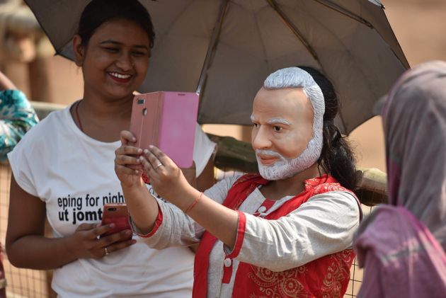 A supporter of Bhartiya Janata Party takes selfie with a face mask of Prime Minister Narendra Modi during...