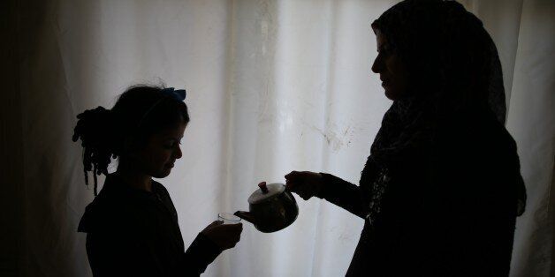 HATAY, TURKEY - APRIL 10: 32 year old Syrian refugee Felek Ramadan, who had been held as a captive by Syrian regime about a month, pour tea for her daughter at her home in Hatay province of Turkey on April 10, 2016. Felek Ramadan who were exposed to beating, insulting and physical violence during his imprisonment in Assad Regime force's prisons in Syria's Homs, tries to start a new life in Turkey's Hatay. (Photo by Cem Genco/Anadolu Agency/Getty Images)