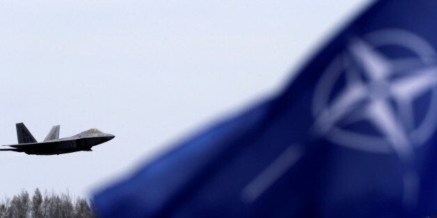 NATO flag flutters as U.S. Air Force F-22 Raptor fighter flies over the military air base in Siauliai, Lithuania, April 27, 2