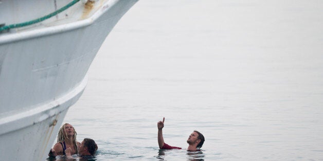 Activists in the sea try to interfere the deportation of Pakistani migrants on board a ferry set to sail for Turkey in the port of Mytilini of the Greek island of Lesbos, Friday, April 8, 2016. Forty-five migrants from Pakistan were deported to Turkey on Friday under the EU agreement with Turkey. (AP Photo/Petros Giannakouris)