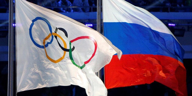 The Russian national flag (R) and the Olympic flag are seen during the closing ceremony for the 2014 Sochi Winter Olympics, Russia, February 23, 2014. REUTERS/Jim Young/File Photo