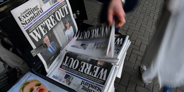 A man takes a copy of the London Evening Standard newspaper with the front page reporting the resignation of British Prime Mi