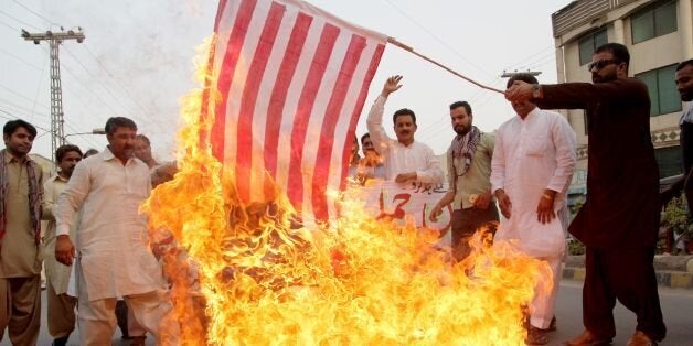 A Pakistani demonstrator holds a burning US flag as others shout slogans during a protest in Multan on May 24, 2016, against