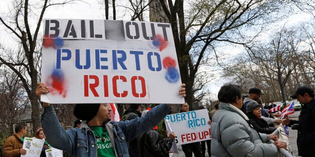 A demonstrator protests the Federal Reserve's failure to bail out Puerto Rico outside International House, Thursday, April 7, 2016, in New York. Federal Reserve chair Janet Yellen appeared with former Federal Reserve chairs Ben Bernanke, Paul Volcker and Alan Greenspan, who appeared via video conference, in a panel designed to address millennial and illuminate how the Chairs' philosophies and personal beliefs impact decision-making with international implications. (AP Photo/Kathy Willens)