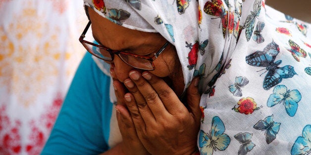A woman mourns for the victims who were killed in the attack on the Holey Artisan Bakery and the O'Kitchen Restaurant, at a m