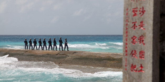 Soldiers of China's People's Liberation Army (PLA) Navy patrol near a sign in the Spratly Islands, known in China as the Nans