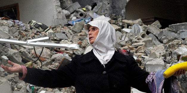 FILE - In this Wednesday, Feb. 6, 2013 file photo, a Syrian woman stands amid the ruins of her house which was destroyed in a