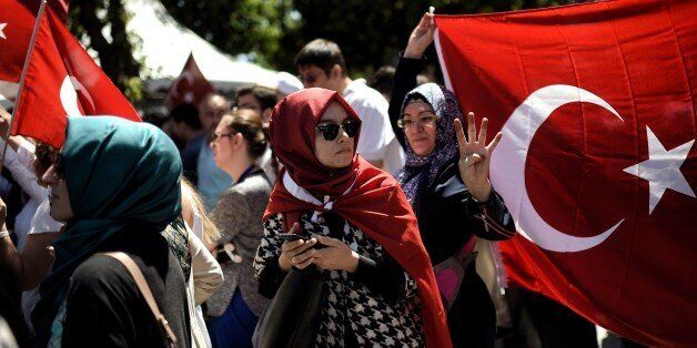 A woman is wrapped in a Turkish flag during a demonstration in support to the Turkish President at the Sarachane park in Istanbul on July 19, 2016. The Turkish army said on July 19 that the vast majority of its members had no links with the July 15 attempted coup and warned that the putschists would face severe punishment. The armed forces blamed the 'Fethullah Terrorist Organisation' (FETO) for the failed putsch, referring to Fethullah Gulen, a one-time ally turned foe of President Recep Tayyip Erdogan. Turkey's prime minister said on July 19 his government had sent four files to the United States, as Ankara seeks the extradition of US-based preacher Fethullah Gulen. / AFP / ARIS MESSINIS (Photo credit should read ARIS MESSINIS/AFP/Getty Images)