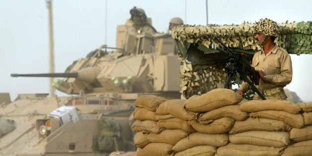 ** FILE ** A member of the Mujahedeen Khalq, or MEK, an Iranian opposition group in Iraq, guards the road leading to the group's main training camp, which is watched over by a U.S. Army Bradley Fighting Vehicle, near Baqubah, north central Iraq, in this May 9, 2003 file photo. As soon as the State Department created a list of terror organizations in 1997, it named the MEK, putting it in a club that includes al-Qaida and barring anyone in the U.S. from providing material support. The State Department says the MEK groups were funded by Saddam Hussein, supported the seizure of the U.S. embassy in Tehran in 1979 and are responsible for the deaths of Americans in the 1970s. (AP Photo/Brennan Linsley/File)