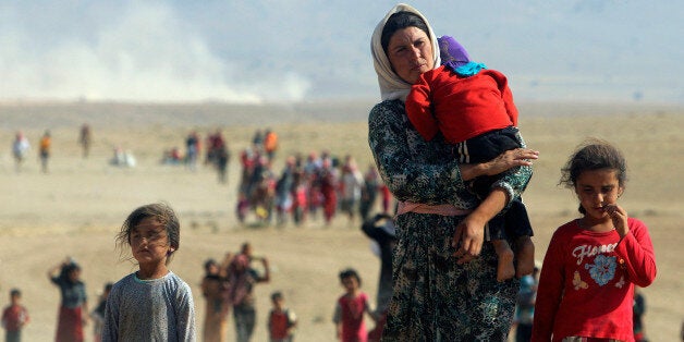 Displaced people from the minority Yazidi sect, fleeing violence from forces loyal to the Islamic State in Sinjar town, walk towards the Syrian border on the outskirts of Sinjar mountain near the Syrian border town of Elierbeh of Al-Hasakah Governorate in this August 11, 2014. REUTERS/Rodi Said/File Photo