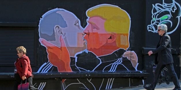 TOPSHOT - People walk past a mural on a restaurant wall depicting US Presidential hopeful Donald Trump and Russian President