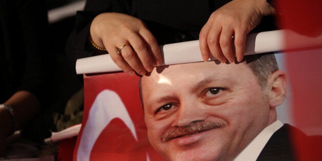 BERLIN, GERMANY - FEBRUARY 04: A supporter of Turkish Prime Minister Recep Tayyip Erdogan unrolls a poster at a rally at Tempodrom hall on February 4, 2014 in Berlin, Germany. Turkey will soon face parliamentary elections and Erdogan is vying for the votes of expatriate Turks. Berlin has the highest Turkish population of any city outside of Turkey. (Photo by Adam Berry/Getty Images)