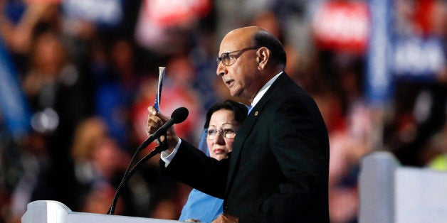 Khizr Khan, father of fallen US Army Capt. Humayun S. M. Khan, holds up his copy the United States Constitution, while his wife Ghazala Khan looks on, as he speaks during the final day of the Democratic National Convention in Philadelphia, Thursday, July 28, 2016. (AP Photo/Paul Sancya)