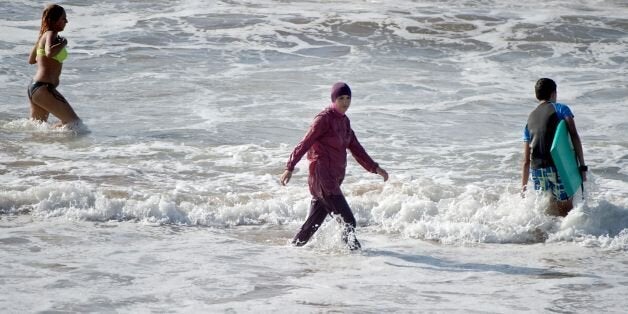 A Moroccan woman wearing a 'burkini' (C), a full-body swimsuit designed for Muslim women, enters the sea at Oued Charrat beach, near the capital Rabat, on August 17, 2016. / AFP / FADEL SENNA (Photo credit should read FADEL SENNA/AFP/Getty Images)