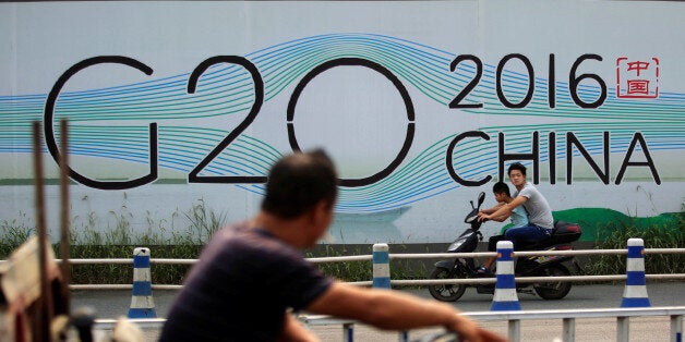 People cycle past a billboard for the upcoming G20 summit in Hangzhou, Zhejiang province, China, July 29, 2016. Picture taken July 29, 2016. REUTERS/Aly Song