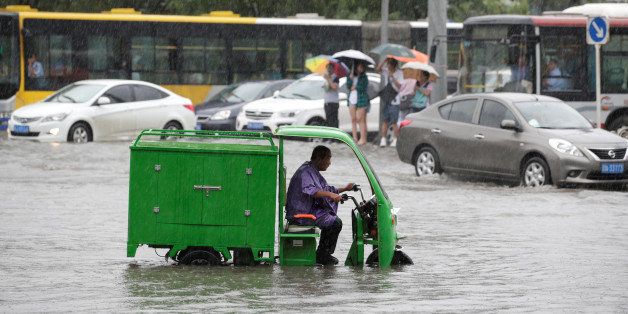 A man rides along a flooded street during a heavy rainfall in Shilipu, Chaoyang Road, Beijing, China July 20, 2016. REUTERS/Jason Lee