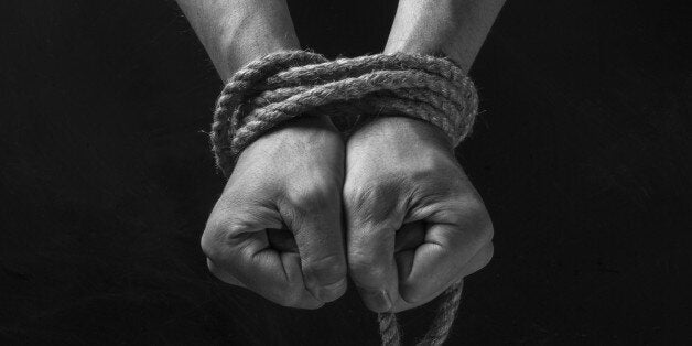 Hands tied with rope on a black background.