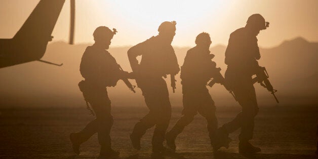 Silhouette of soldiers near helicopter in desert landscape