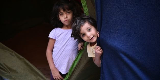 Refugee children peer out from their tent at the municipality-run Souda camp on the Greek island of Chios on September 29, 2016. Greece is accommodating over 60,000 refugees and migrants stuck in the country after a succession of Balkan and EU states shut their borders earlier this year. / AFP / LOUISA GOULIAMAKI (Photo credit should read LOUISA GOULIAMAKI/AFP/Getty Images)