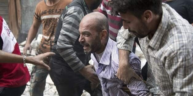 A grief-striken Syrian man is comforted by people as rescuers pull the body of his daughter from the rubble of a budling following government forces air strikes in the rebel held neighbourhood of Al-Shaar in Aleppo on September 27, 2016. Syria's army took control of a rebel-held district in central Aleppo, after days of heavy air strikes that have killed dozens and sparked allegations of war crimes. / AFP / KARAM AL-MASRI (Photo credit should read KARAM AL-MASRI/AFP/Getty Images)