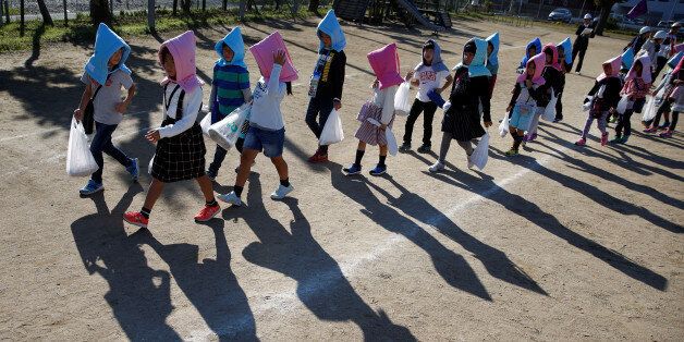 School children wearing padded hoods to protect them from falling debris make their way to an evacuation shelter on a hill during a tsunami simulation drill ahead of World Tsunami Awareness Day at Futaba elementary school in Choshi, Chiba Prefecture, Japan, November 4, 2016. REUTERS/Kim Kyung-Hoon