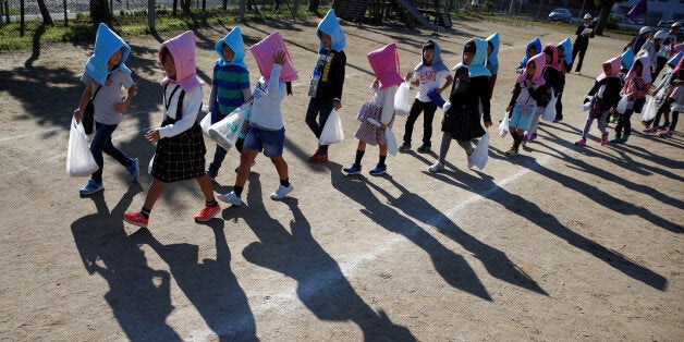 School children wearing padded hoods to protect them from falling debris make their way to an evacuation shelter on a hill during a tsunami simulation drill ahead of World Tsunami Awareness Day at Futaba elementary school in Choshi, Chiba Prefecture, Japan, November 4, 2016. REUTERS/Kim Kyung-Hoon