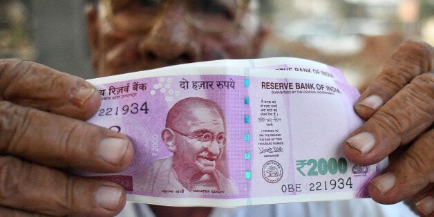 A man holds new Indian two thousand rupee banknotes for a photograph outside a bank in Dadri, Uttar Pradesh, India, on Tuesday, Nov. 15, 2016. Over a week since Prime Minister Narendra Modi shocked the nation with the withdrawal of large denomination notes there was no sign the government had managed to print enough notes to replace its withdrawal of 86 per cent of currency in circulation. Photographer: Anindito Mukherjee/Bloomberg via Getty Images