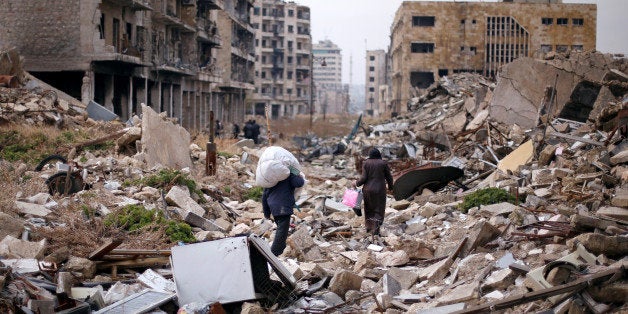 People walk amid the rubble as they carry belongings that they collected from their houses in the government controlled area