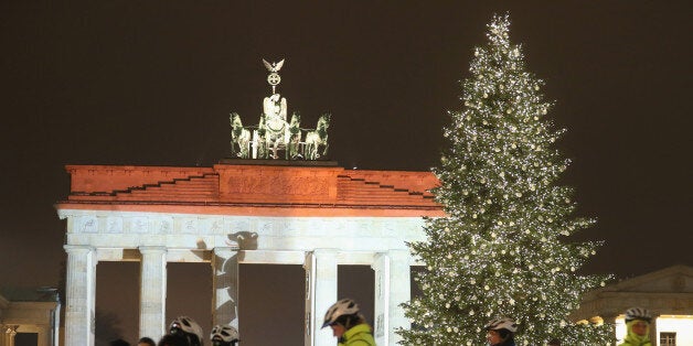 BERLIN, GERMANY - DECEMBER 20: The Brandenburg Gate stands illuminated in the colors of the Berlin flag as bicycle-mounted p