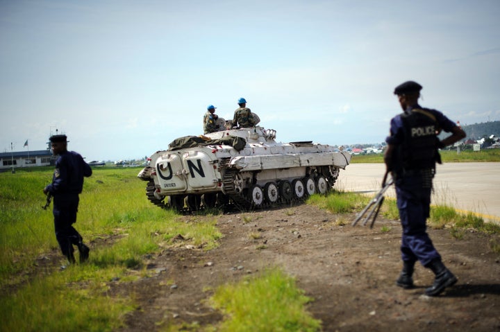 Congolese government policemen walk on December 4, 2012 alongside the runway near to a United Nations armoured personnel carrier at the airport in Goma, eastern Democratic Republic of the Congo, during a visit by Congo's interior minister. The airport was held by United Nations forces whilst M23 overran the city two weeks ago, before leaving on December 1. Government troops returned to the city on December 3. AFP PHOTO/PHIL MOORE (Photo credit should read PHIL MOORE/AFP/Getty Images)