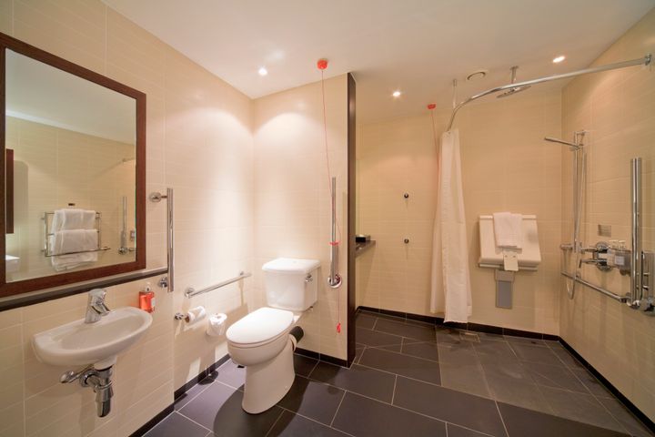 An accessible ensuite bathroom with chrome grab rails at the Radisson Edwardian Hotel, a luxury hotel located in London's Canary Wharf., Canary Wharf, London, London, England.