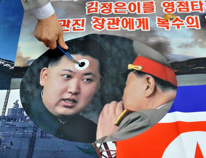 A South Korean activist stabs a pocket knife on a picture of North Korean leader Kim Jong-Un (L) during an anti-North Korea rally near the national assembly in Seoul on March 22, 2013. North Korea posted a new propaganda video on March 22, showing paratroopers descending on Seoul in an invasion scenario that envisages taking around 150,000 US residents in South Korea hostage. AFP PHOTO / JUNG YEON-JE (Photo credit should read JUNG YEON-JE/AFP/Getty Images)