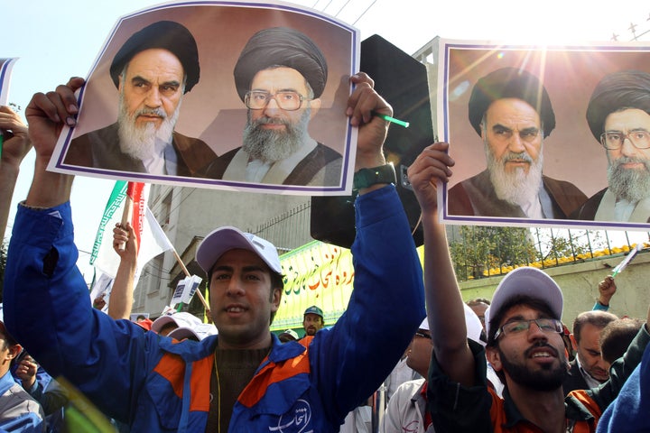 Workers of Iran's Entekhab Industrial Group hold portraits of late founder of Islamic republic, Ayatollah Ruhollah Khomeini (L) and supreme leader, Ali Khamenei (R) as they demonstrate in front of the South Korean embassy in Tehran on October 21, 2012, after an acquisition deal inked with Daewoo Electronics in 2010 went sour due to sanctions. The demo by the privately owned Iranian company was aimed at retrieving the downpayment of $70 million (around 53 million euros) Entekhab paid in 2011 to Daewoo, a company's spokesman told AFP. AFP PHOTO/ATTA KENARE (Photo credit should read ATTA KENARE/AFP/Getty Images)